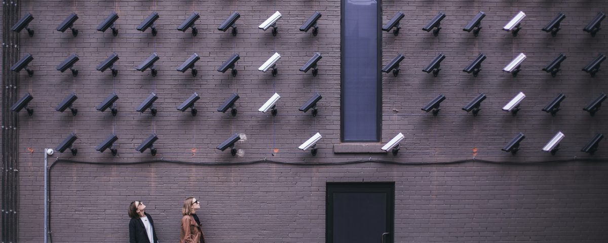 image montrant des caméras et deux femmes près de l'entrée d'une porte. L'image suggeère un système de surveillance poussé.