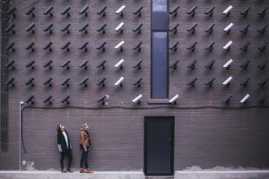 image montrant des caméras et deux femmes près de l'entrée d'une porte. L'image suggeère un système de surveillance poussé.