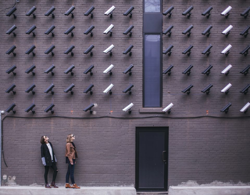 image montrant des caméras et deux femmes près de l'entrée d'une porte. L'image suggeère un système de surveillance poussé.